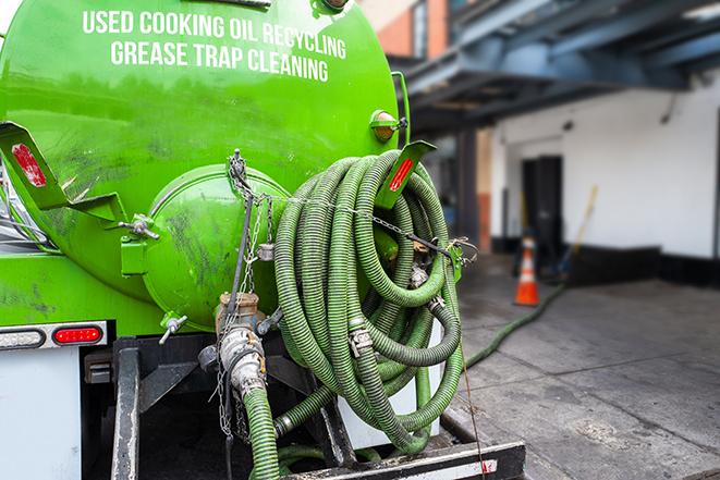 a professional plumber using a pump to empty a grease trap in Anaheim, CA